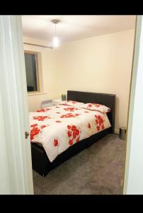 um quarto com uma cama com flores vermelhas em 2 bedroom apartment city centre Birmingham em Birmingham