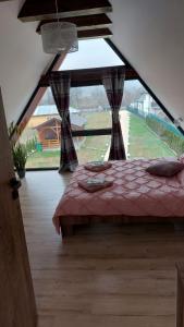a bedroom with a bed and a large window at Cabana A-frame Nis in Coţofăneşti