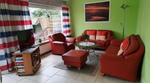 a living room with red chairs and a television at Haus Christine in Wremen