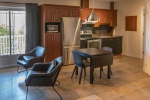 a kitchen with a table and chairs and a refrigerator at Appartements Victoria in La Baie