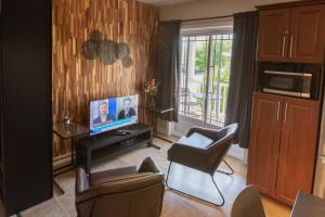 a living room with a flat screen tv and chairs at Appartements Victoria in La Baie