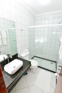 a bathroom with a toilet, sink, and shower stall at Hotel Plaza Mar in Vila Velha