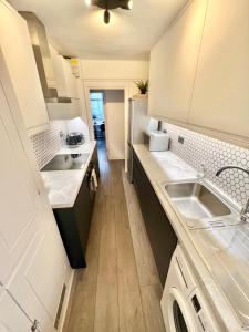 - une cuisine avec des placards blancs et un évier dans l'établissement Modern apartment in Fulham, à Londres
