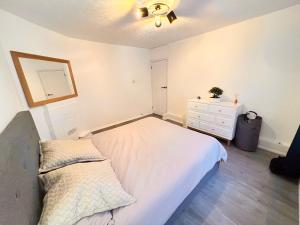 - une chambre blanche avec un lit et une commode dans l'établissement Modern apartment in Fulham, à Londres