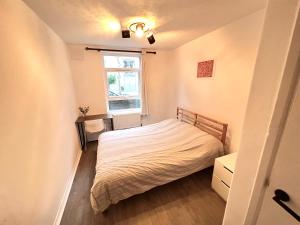 - une petite chambre avec un lit et une fenêtre dans l'établissement Modern apartment in Fulham, à Londres