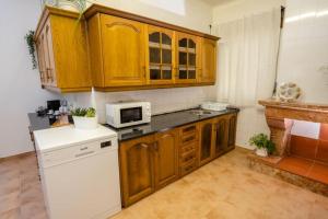 - une cuisine avec des placards en bois et un réfrigérateur blanc dans l'établissement Quinta dos Pinheiros, à Estanqueiro