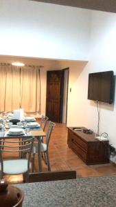 a dining room with a table and a flat screen tv at casa tropero sosa in Maipú