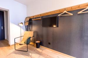 um quarto com uma parede com uma televisão e uma cadeira em Gyger Restaurant Confiserie B&B em Thusis