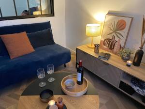 een woonkamer met een blauwe bank en een tafel met wijnglazen bij Maison Hyper centre-Hôpital et parking in Moulins