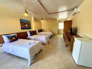 a hotel room with two beds and a television at Arena Carneiros Hotel by AFT in Tamandaré