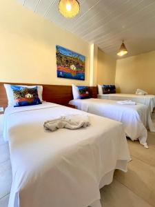 Cette chambre comprend 3 lits avec des draps blancs. dans l'établissement Arena Carneiros Hotel by AFT, à Tamandaré