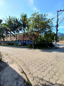 a cobblestone street with palm trees and a house at Chales Arco-iris 2 - Para quem procura simplicidade em uma ótima localização in Ilhabela +8 photos