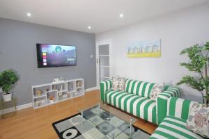 un soggiorno con 2 divani a righe verdi e una TV di Stunning 3 Bedroom 2 Bathroom Bungalow by CozyNest a Earley