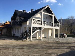 a large white house with a balcony and a car at Cztery Pokoje Wetlina in Wetlina