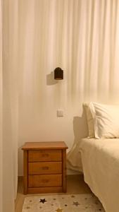 a bedroom with a bed and a wooden nightstand with a bedskirts at Na Casa da Fátima in Vila Nova de Milfontes