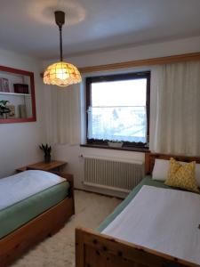 a bedroom with two beds and a window and a chandelier at Ferienhaus Gastein in Bad Hofgastein