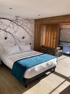 a bedroom with a bed with a tree mural on the wall at Appart Hôtel Le JAS in Ancelle