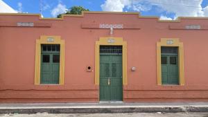 un edificio rosa con dos puertas verdes en Nuik Casa Tropical, en Mérida