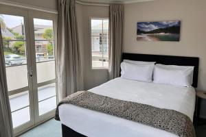 a bedroom with a bed and a large window at Silver Fern Rotorua Suites & Spa in Rotorua