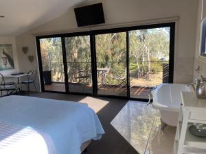 a bedroom with a bed and a tub and a balcony at Adelphi Apartments 3 or 3A - Downstairs 2 Bedroom or Upstairs King Studio with Balcony in Echuca