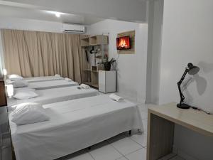 ParagominasにあるHotel Goytacáのベッド3台と暖炉が備わるホテルルーム