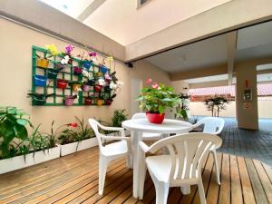 un patio con una mesa blanca, sillas y flores en Apartamento praia Canasvieiras, Florianópolis/SC, en Florianópolis