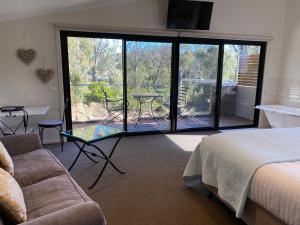 ein Schlafzimmer mit einem Bett und einem Sofa sowie einem Balkon in der Unterkunft Adelphi Apartments 3 or 3A - Downstairs 2 Bedroom or Upstairs King Studio with Balcony in Echuca