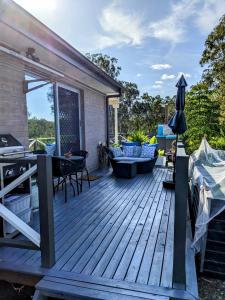 eine Holzterrasse mit einem Tisch und Stühlen in der Unterkunft Scenic Sunsets@Tamborine in Tamborine