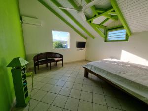 um quarto com uma cama, uma cadeira e uma janela em Villa Caraïbes em Sainte-Rose