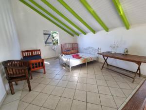 um quarto com uma cama, uma mesa e cadeiras em Villa Caraïbes em Sainte-Rose