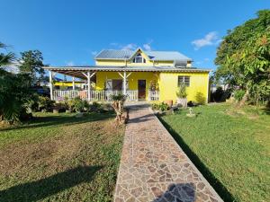 uma casa amarela com um passadiço à sua frente em Villa Caraïbes em Sainte-Rose