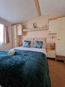 a bedroom with a large bed with a green blanket at Caravan in the Cotswolds in Cirencester