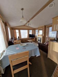 ein Wohnzimmer mit einem Tisch und einem Sofa in der Unterkunft Caravan in the Cotswolds in Cirencester