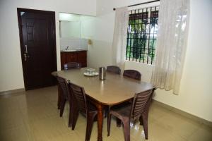 a dining room with a wooden table and chairs at Dinesh's Nest with Balcony View in Chikmagalūr