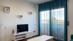 een woonkamer met een tv en een groot raam bij Apartamento Delta in Deltebre