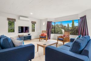 uma sala de estar com cadeiras azuis e uma televisão em Regent Retreat - Martinborough Holiday Home em Martinborough