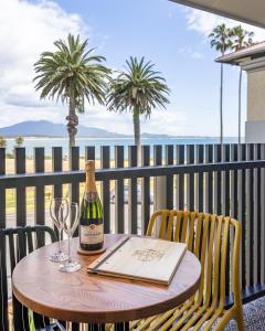 伯馬吉的住宿－Bermagui Beach Hotel，阳台上的桌子上摆放着一瓶葡萄酒