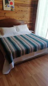 una cama con una manta a rayas encima en Casa en Villarrica con vista al Volcán, en Molco
