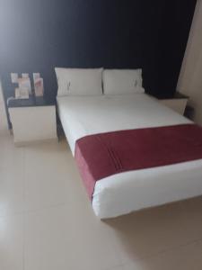 a bedroom with a white bed with a red blanket at HOTEL MORELOS in Guadalajara
