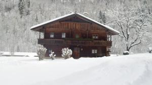 una grande casa in legno nella neve con la neve di Pension Schwaighof a Oberau