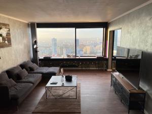 een woonkamer met een bank en een tafel en een groot raam bij Plus haut jacuzzi d’Europe, 40e étage in Puteaux