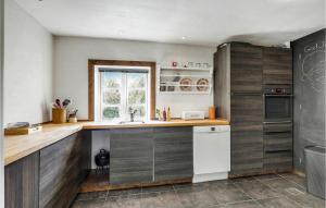 a kitchen with wooden cabinets and a sink and a refrigerator at 6 Bedroom Cozy Home In Gudhjem in Gudhjem