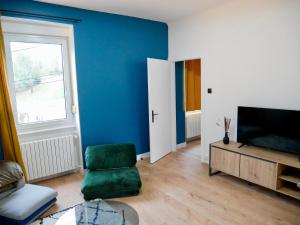 a living room with a green chair and a television at Le nid douillet de Sarreguemines in Sarreguemines