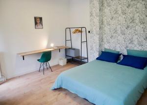 a bedroom with a blue bed and a desk at Le nid douillet de Sarreguemines in Sarreguemines