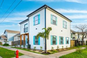 uma casa branca com janelas azuis e uma palmeira em Sea Cove em Galveston