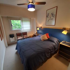 1 dormitorio con 1 cama azul y ventilador de techo en Departamento céntrico con cochera. en Buenos Aires