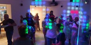 grupa ludzi tańczących w pokoju z kolorowymi światłami w obiekcie RIWIERA Dźwirzyno w Dźwirzynie
