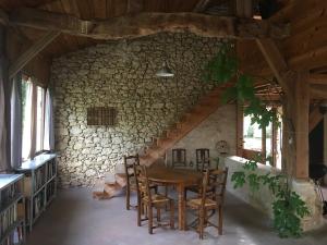 a dining room with a wooden table and chairs at Grange en Maurille in Sirac