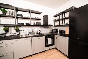 a kitchen with white cabinets and a black refrigerator at Apartment Na Skále CLOSE TO CITY CENTER & SKI LIFT in Špindlerův Mlýn