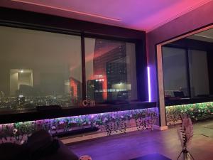 een kamer met een raam met paarse verlichting en bloemen bij Plus haut jacuzzi d’Europe, 40e étage in Puteaux